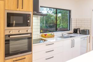 a kitchen with a microwave oven and a sink at Birds 'n' Bloom Cottages in Yungaburra