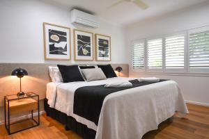 a bedroom with a large bed and two windows at Birds 'n' Bloom Cottages in Yungaburra