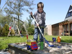 un joven jugando con un camión de juguete en un arenero en Utesch's Ferienwohnungen, en Neuharlingersiel