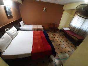 Cette chambre comprend 2 lits et une fenêtre. dans l'établissement HOTEL CAVERI COMFORT INN, à Madikeri