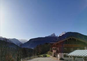 un grande edificio con montagne sullo sfondo di Gästehaus Obersulzberglehen a Schönau am Königssee