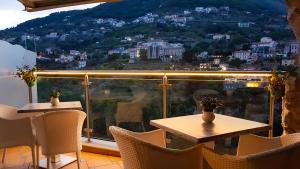 a balcony with tables and chairs and a view of a city at Le Perle d'Italia in Ravello