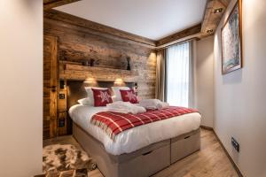 een slaapkamer met een bed en een houten muur bij Alaska Lodge by Alpine Resorts in Val dʼIsère