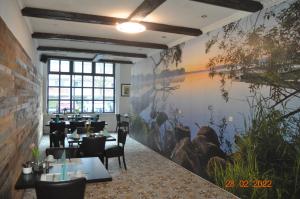 a dining room with tables and chairs and a painting on the wall at Parkhotel Schwedt in Schwedt