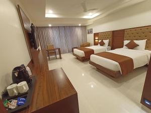 a hotel room with two beds and a television at Ananth The Grand in Hubli