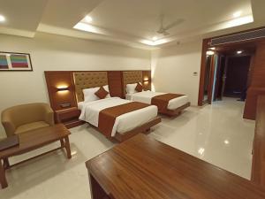 a hotel room with two beds and a chair at Ananth The Grand in Hubli