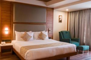 a hotel room with a bed and two chairs at Ananth The Grand in Hubli