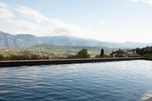 uma piscina de água com montanhas ao fundo em Ansitz Montani Eppan em Appiano sulla Strada del Vino