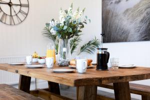 un tavolo in legno con cibo e un vaso di fiori di Seascape a Penzance