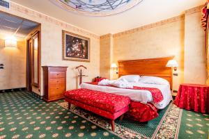 a hotel room with a bed and a red chair at Hotel Cristallo in Sestriere