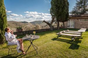 une femme assise sur une chaise à une table dans une cour dans l'établissement Castello di Spaltenna Exclusive Resort & Spa, à Gaiole in Chianti