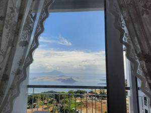 a window with a view of a mountain at 1 BR Cozy Farmhouse-Style Condo with Balcony & Taal View at Wind Residences in Tagaytay