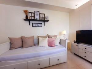 a bedroom with a bed with pillows and a tv at 1 BR Cozy Farmhouse-Style Condo with Balcony & Taal View at Wind Residences in Tagaytay