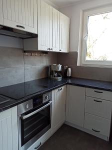 a kitchen with white cabinets and a black counter top at Na Sadowej in Grodzisk Mazowiecki