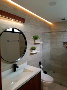 a bathroom with a sink and a mirror and a toilet at Kapital Suites in Pereira