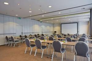 a conference room with tables and chairs and a projection screen at H+ Hotel Stuttgart Herrenberg in Herrenberg