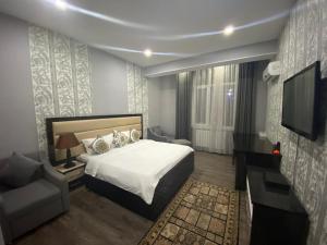 um quarto com uma cama, uma televisão e um sofá em Sunrise Apartments em Dushanbe