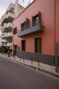 un bâtiment rose avec un balcon sur le côté d'une rue dans l'établissement Vagabond Guesthouse, à Athènes