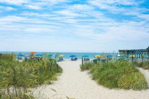 un camino de arena que conduce a una playa con sombrillas en Snorkel Way, en Myrtle Beach