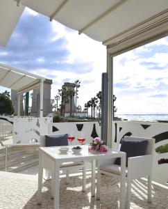 - une table et des chaises blanches avec des verres à vin sur la terrasse dans l'établissement Piccadilly Rooms Restaurant and Beach, à Santa Maria al Bagno