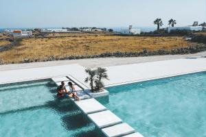 un grupo de tres personas de pie junto a una piscina en Adama Mykonos Boutique Hotel en Mykonos