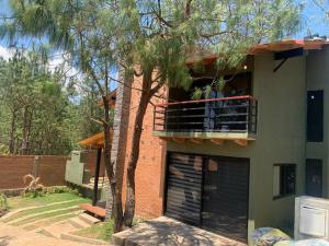 un edificio con balcón y un árbol en Cabaña de Lujo LA HERRADURA, Mazamitla, en Mazamitla