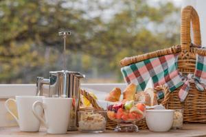 un tavolo per la colazione con un cesto di pane e tazze di The Carriages Boutique Hotel and Vineyard a Pokolbin