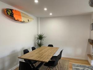 uma sala de jantar com uma mesa de madeira e uma prancha de surf na parede em Casa da Sofia em Leça da Palmeira