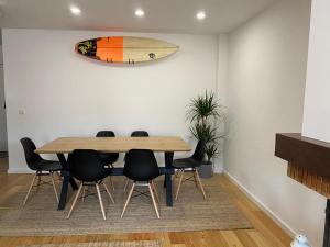 uma sala de jantar com uma mesa e uma prancha de surf na parede em Casa da Sofia em Leça da Palmeira