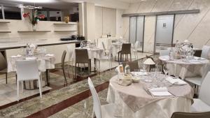 una sala da pranzo con tavoli e sedie con tovaglie bianche di Alfa Fiera Hotel a Vicenza