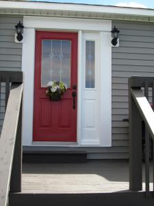 una porta rossa con un vaso di fiori su una casa di The Bayside Bed and Breakfast a Bareneed