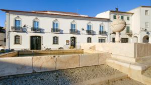 un grande edificio bianco con una statua davanti di MouraSuites Hotel a Évora