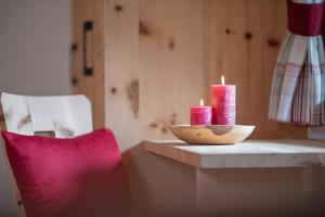 two candles sitting on a table next to a chair at Oberglarzhof App Zirbel in Villnoss