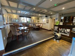 un restaurant avec une table et des chaises ainsi qu'un bar dans l'établissement Tollemache Arms, à Calveley