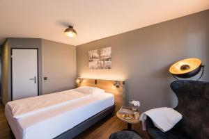 um quarto de hotel com uma cama e uma cadeira em Aarau West Swiss Quality Hotel em Oberentfelden