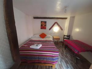 Dormitorio pequeño con cama y mesa en Hostal Raymi, en Ollantaytambo