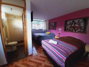 1 dormitorio con 2 camas y pared púrpura en Hostal Raymi, en Ollantaytambo