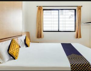 a bedroom with a bed with yellow and blue pillows at Hotel Rahi in Nashik