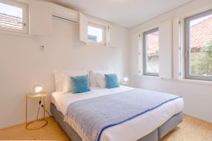 1 dormitorio blanco con 1 cama grande con almohadas azules en YOUROPO - Taipas, en Oporto