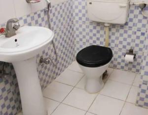 a bathroom with a black toilet and a sink at Hotel Rahi in Nashik