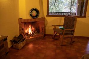 a living room with a fireplace and a chair at Complejo Rural Las Palomas in Jerte