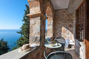 une terrasse avec une table et des chaises et l'océan dans l'établissement Kalamitsi Hotel, à Kardamyli