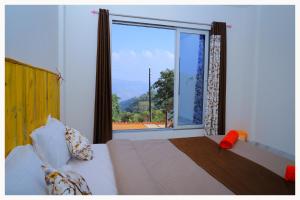 um quarto com uma cama e uma grande janela em Sai Siddhigiri Villa em Mahabaleshwar