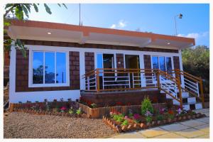 une maison avec une terrasse couverte et des fleurs devant elle dans l'établissement Sai Siddhigiri Villa, à Mahabaleshwar