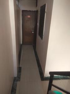 um corredor com uma porta de madeira e um piso com um corredor em Sai Ganesh Guest House em Shirdi