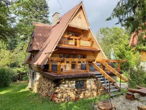 uma casa de madeira com uma varanda em cima em Dacza Zakątek em Falsztyn