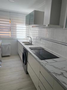 Precioso apartamento a 50 metros de la playa في مليلية: مطبخ أبيض مع حوض وغسالة صحون