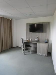 Zimmer mit einem Schreibtisch und einem TV an der Wand in der Unterkunft Businesshotel & Appartements Stuttgart-Vaihingen in Stuttgart