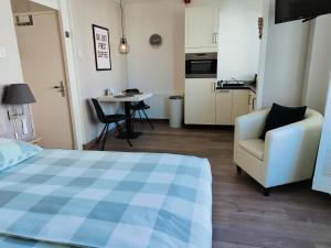 a bedroom with a bed and a chair and a kitchen at Zeehuis Zandvoort in Zandvoort