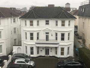 uma casa branca com dois carros estacionados num parque de estacionamento em Rockmount Court em Bournemouth